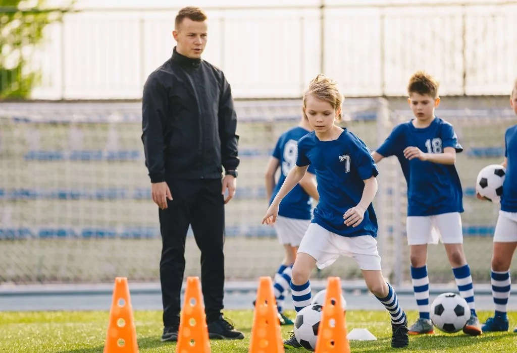 Soccer player dribbling through cones.