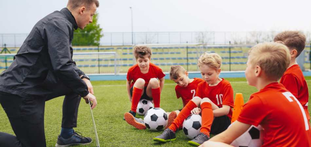 Soccer coach & player huddle on field.