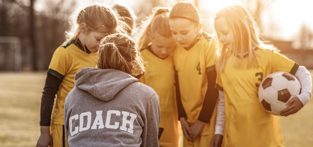Coach and youth soccer players in huddle.