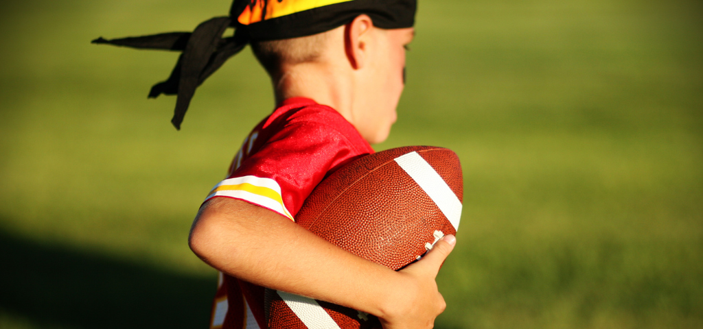Youth football player with ball in hand.