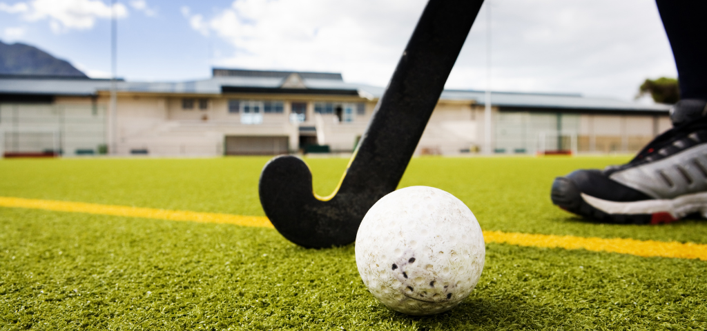 Field hockey ball and stick on field.