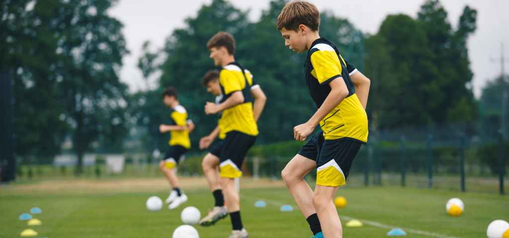 Soccer players doing toe taps on ball.