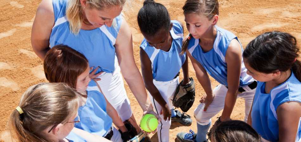 Softball coach and players in huddle.
