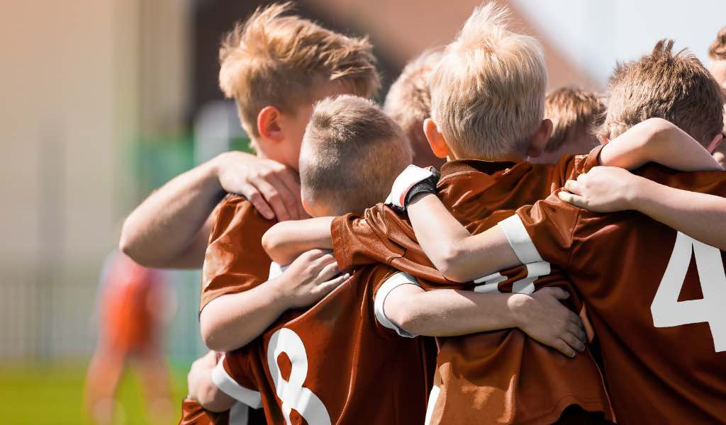 Young athletes in huddle on field.