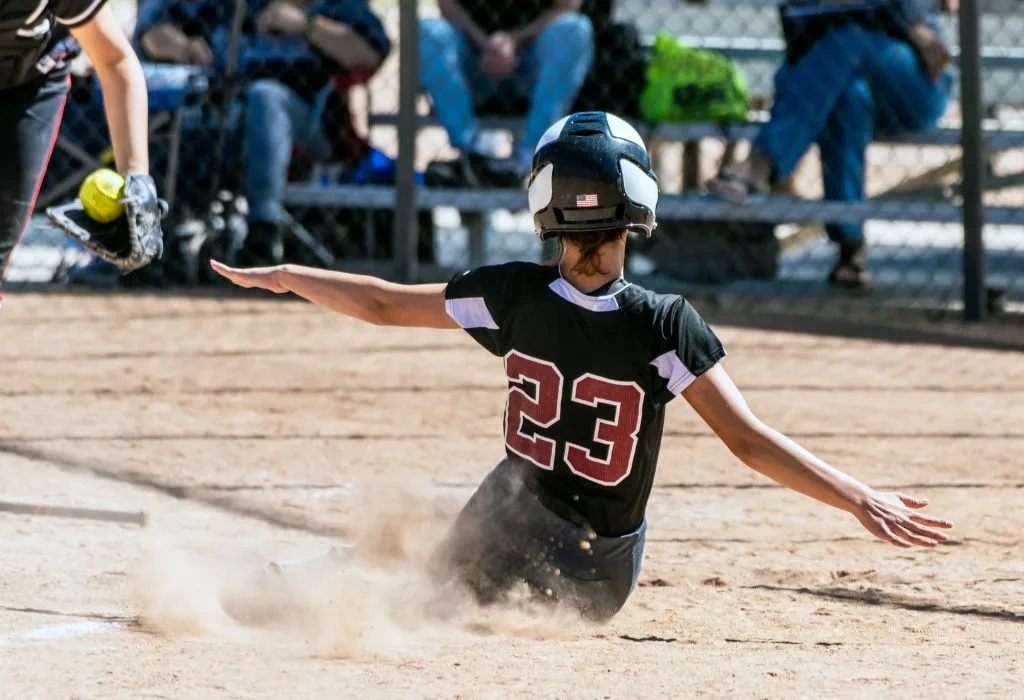 Softball player sliding on base.