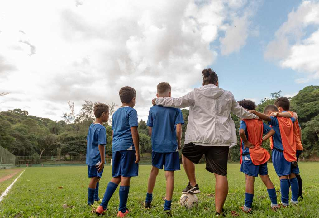 Coach and soccer players in huddle on field.