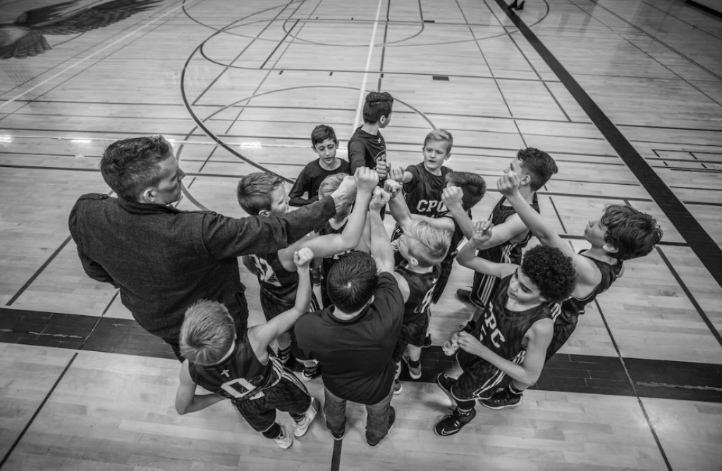 Coach and team huddle on basketball court.