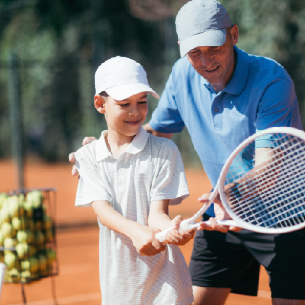 Coach helping tennis player hold racket.