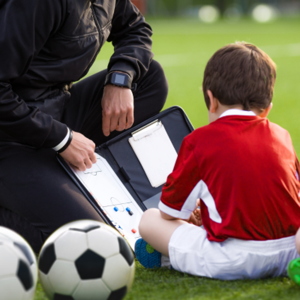 Soccer coach & player on field.