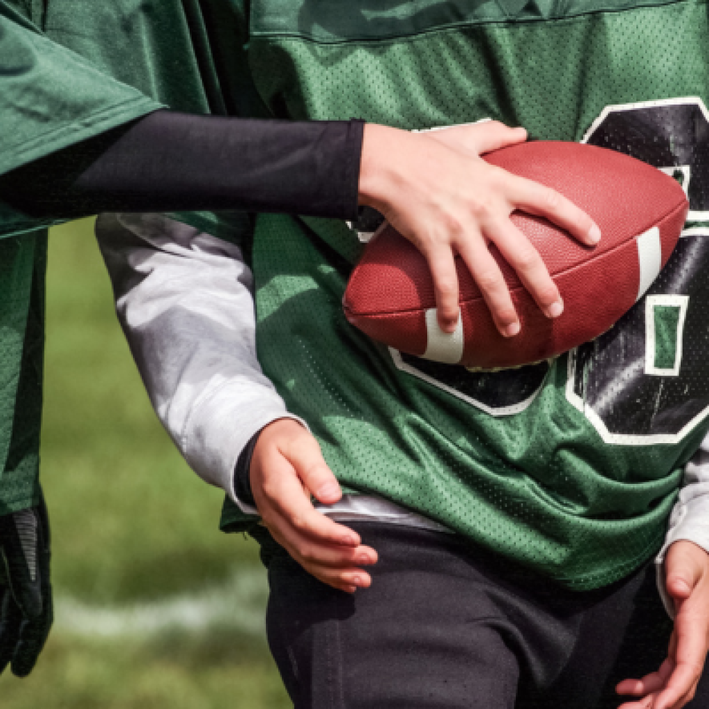 Youth football player with ball in hand.
