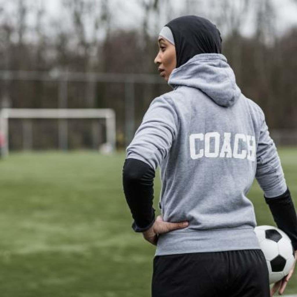 Soccer coaching holding ball by hip.