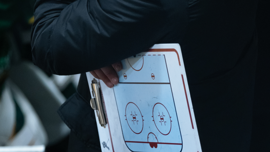 Coach with clipboard under arm.