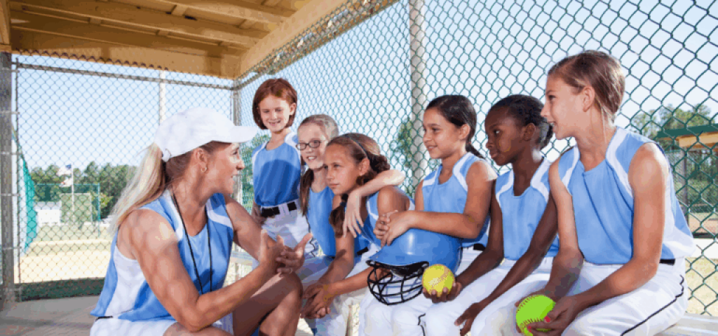Softball coach encouraging players on bench.