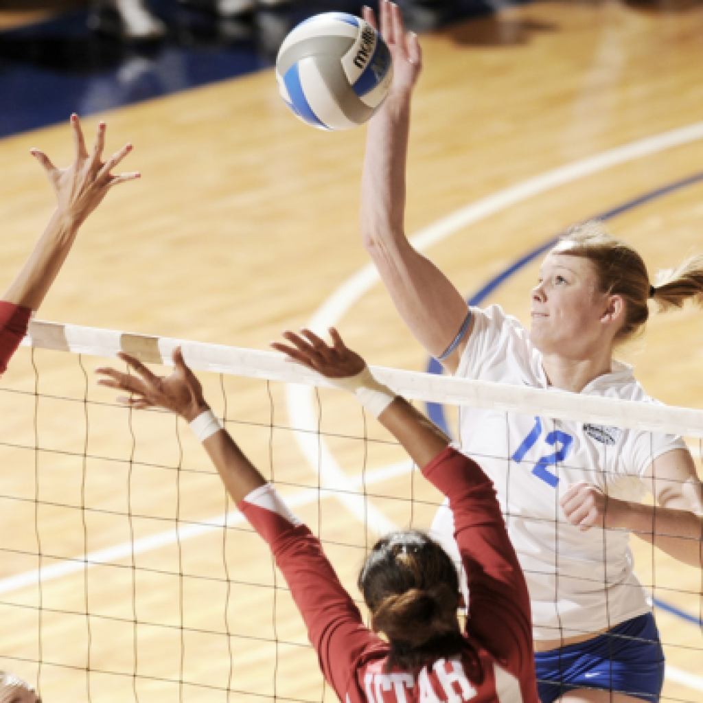 Volleyball player jumping to hit ball.